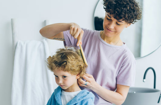 Eine bunte Kinderbürste mit weichen Borsten, ideal für die sanfte Haarpflege von Kindern, auf einem hellen Hintergrund, umgeben von fröhlichen Farben.